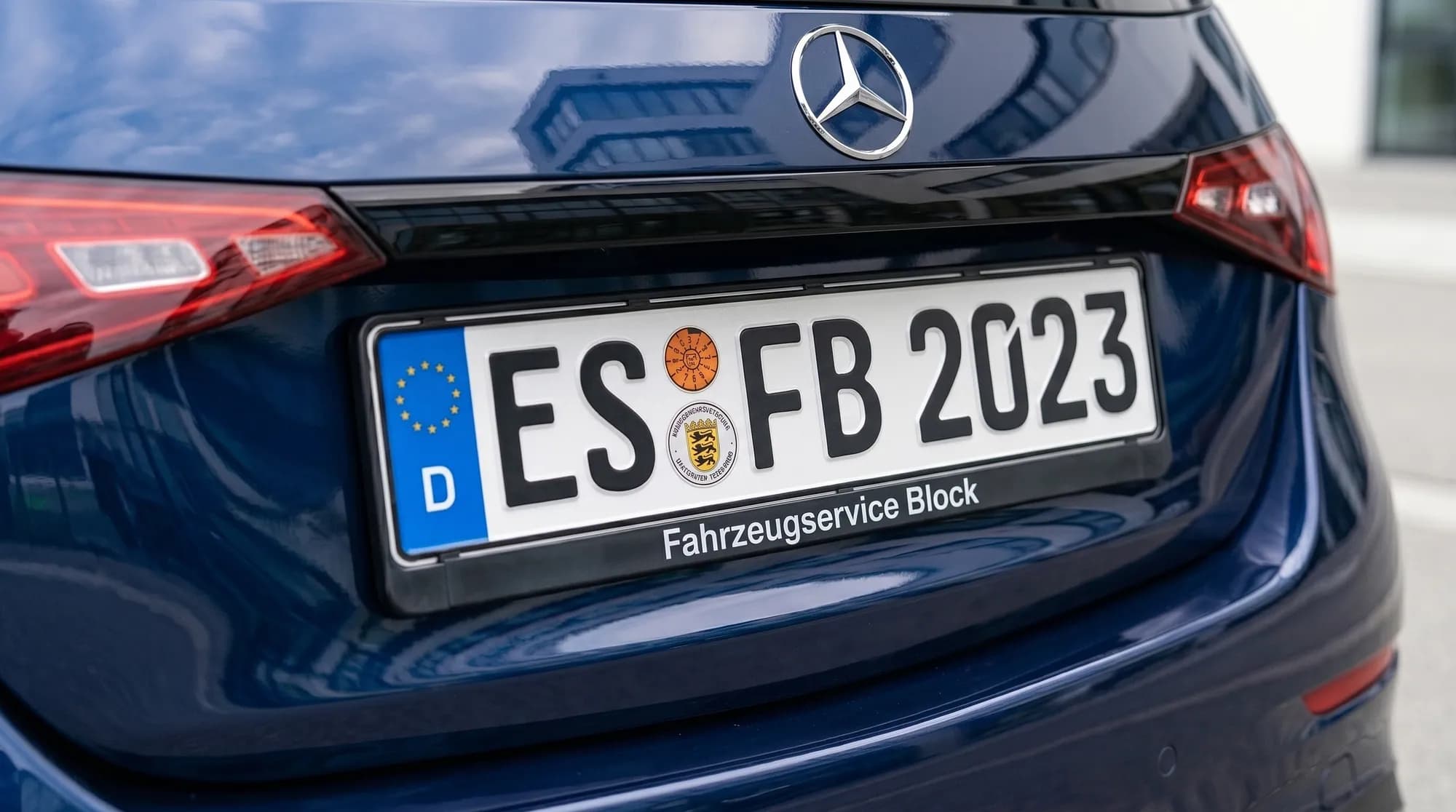 Heck eines dunkelblauen Mercedes: auf dem hinteren Kennzeichen ES FB 2023 im Rahmen mit der Aufschrift Fahrzeugservice Block klebt die runde orange Prüfplakette der Hauptuntersuchung, daneben das Zulassungssiegel
